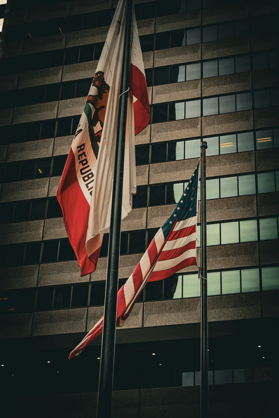 The California state flag and the United States flag in front of an office building