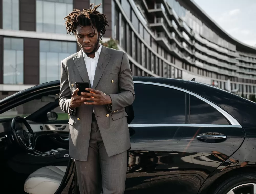A salesperson on his phone beside a new vehicle