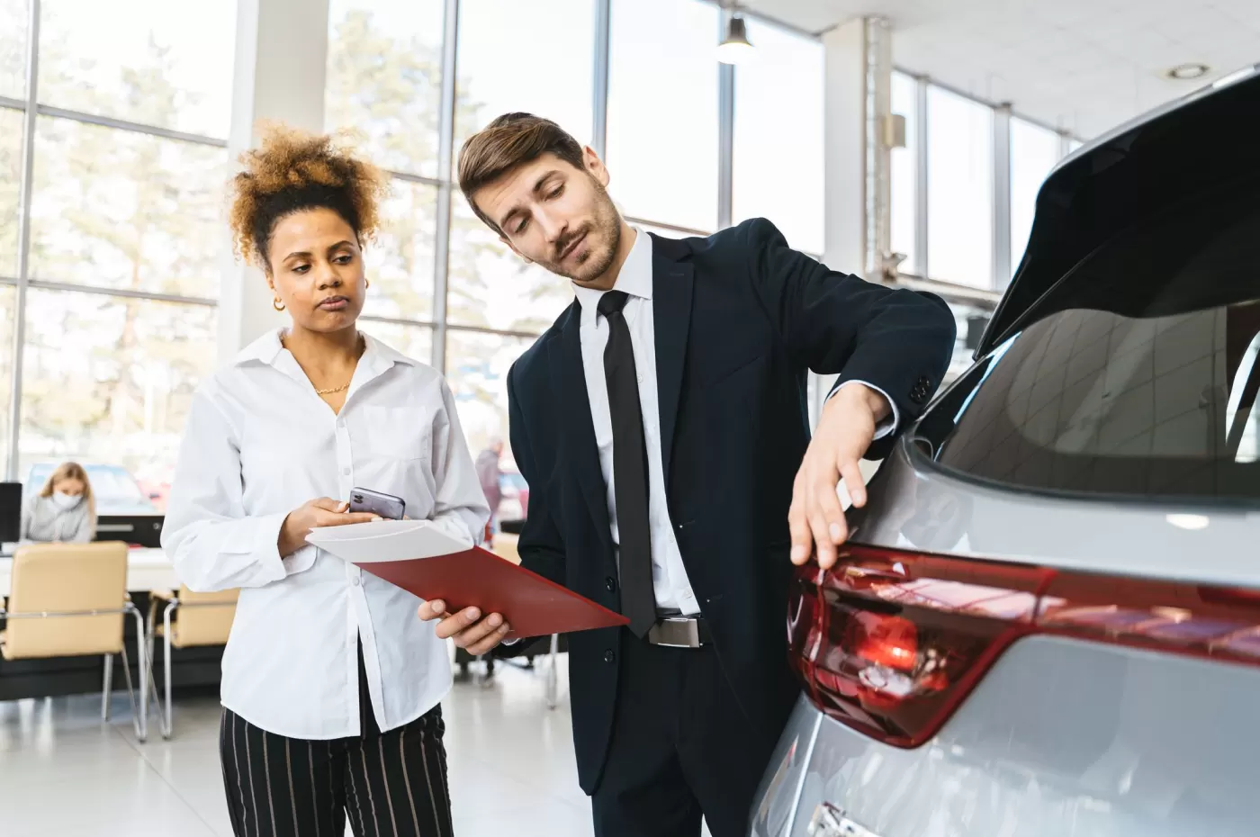 A salesperson showing a customer the details of a vehicle on the showroom floor